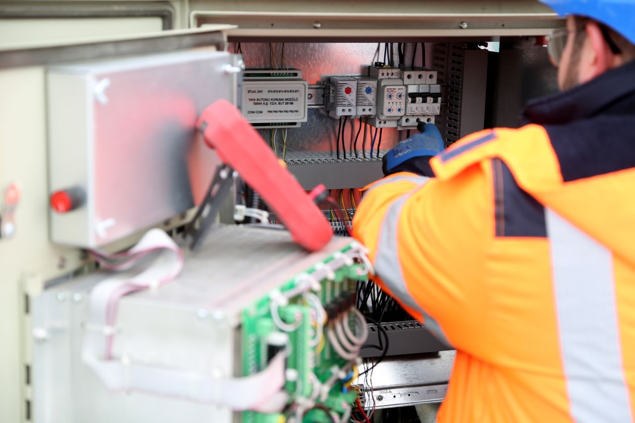 about-us-02 Professional engineer inspecting industrial electrical circuit board, ensuring safety standards.