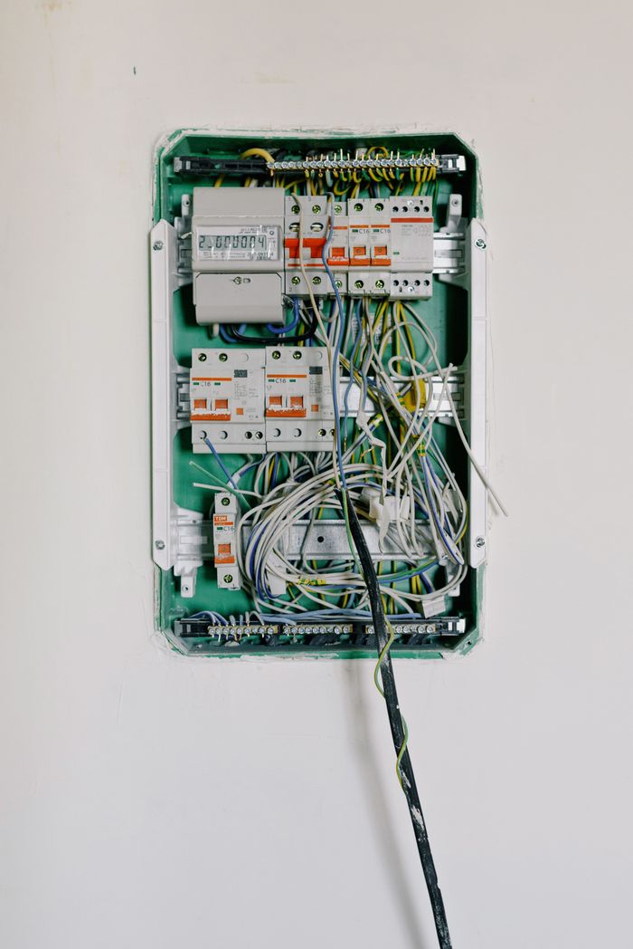 about-us-01 Switchboard with wires connected to electrical switches with circuit breakers installed on white wall